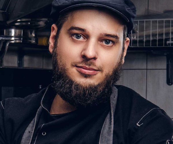 bearded-cook-in-black-uniform-and-hat-holds-knife-BMEASJV.jpg